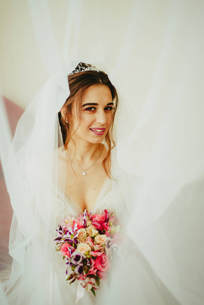 In a wedding dress with the bouquet in her hands. Bride with bouquet on white background - Foto, immagini