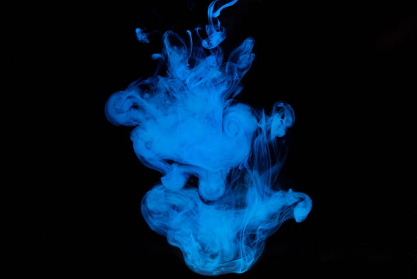 Blaue Farbe löst sich in Wasser auf schwarzem Grund. Aquarellfarbe im Wasser - Foto, Bild