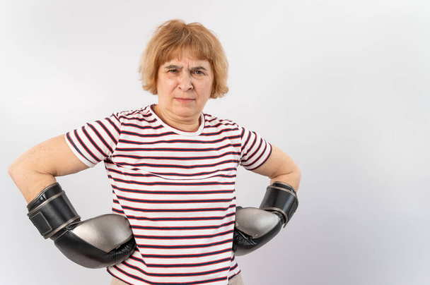 Elderly woman in fighting gloves in a defensive pose on a white background. - Фото, зображення