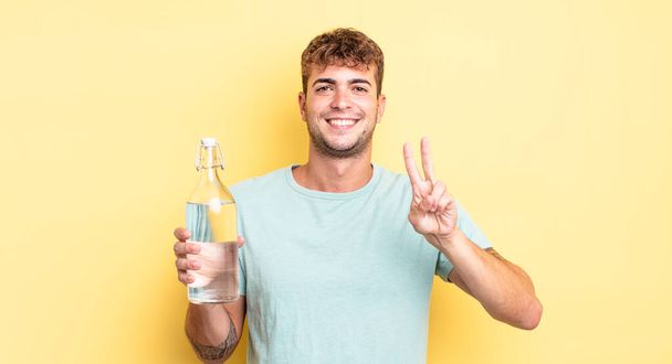 young handsome man smiling and looking friendly, showing number two. water concept - Foto, Imagem