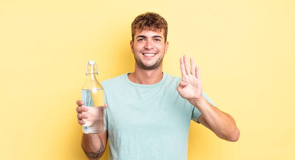 young handsome man smiling and looking friendly, showing number four. water concept - Fotografie, Obrázek