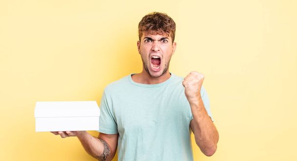 young handsome man shouting aggressively with an angry expression. white box concept - Photo, Image