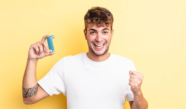 young handsome man feeling shocked,laughing and celebrating success. asthma concept - Fotoğraf, Görsel