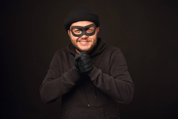 Portrait of funnu thief with mask over dark back - Фото, изображение