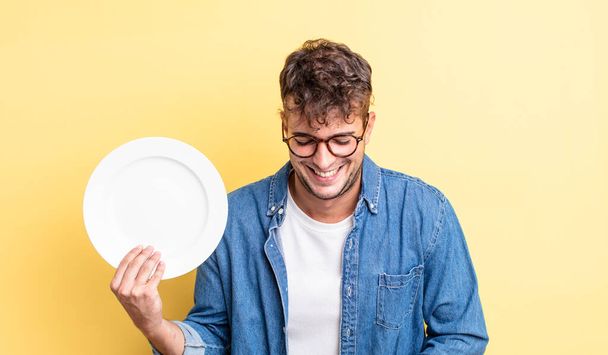 young handsome man laughing out loud at some hilarious joke. empty dish concept - Фото, зображення