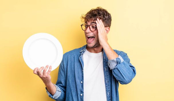 young handsome man feeling happy, excited and surprised. empty dish concept - Photo, image