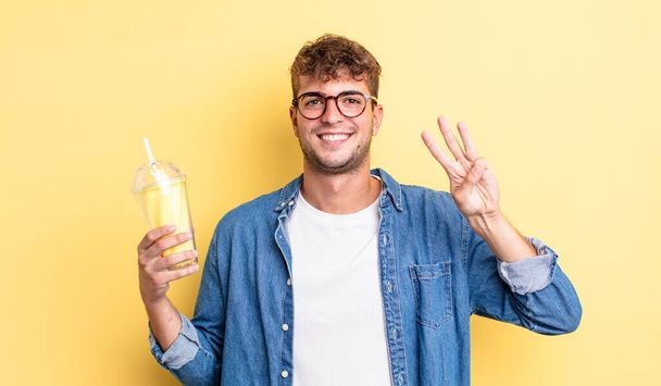 young handsome man smiling and looking friendly, showing number three. milkshake concept - 写真・画像