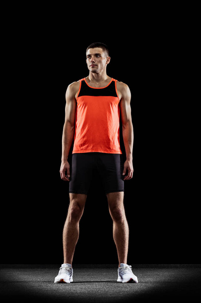 Full-length back view portrait of young male professional athlete isolated over black studio background - Foto, Imagem