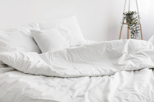 Cama macia e desfeita, travesseiro confortável, roupa de cama branca sem ninguém - Foto, Imagem