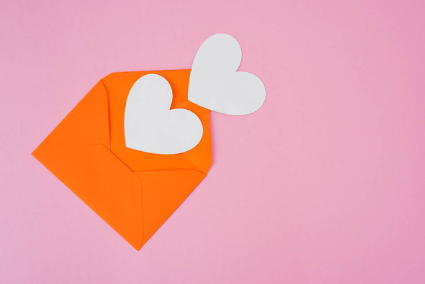 Два белых сердца и конверт на розовом фоне с копировальным пространством. - Фото, изображение