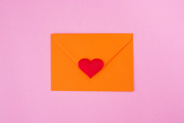 Красное сердце и конверт на розовом фоне - Фото, изображение