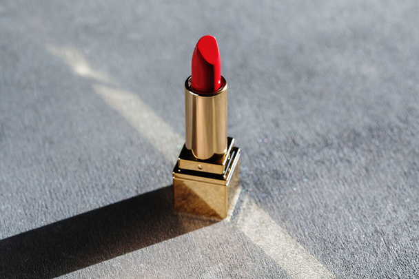 Red lipstick in golden tube on grey background, luxury cosmetics concept - Valokuva, kuva