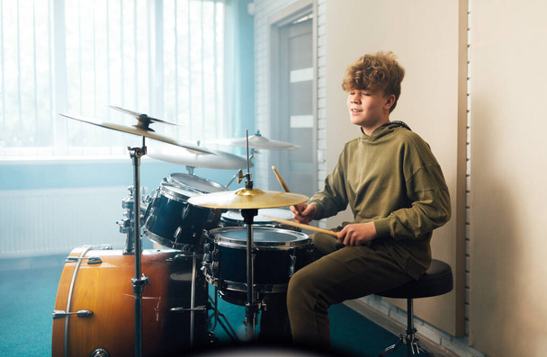 A boy enjoys music playing the drum set - Фото, зображення