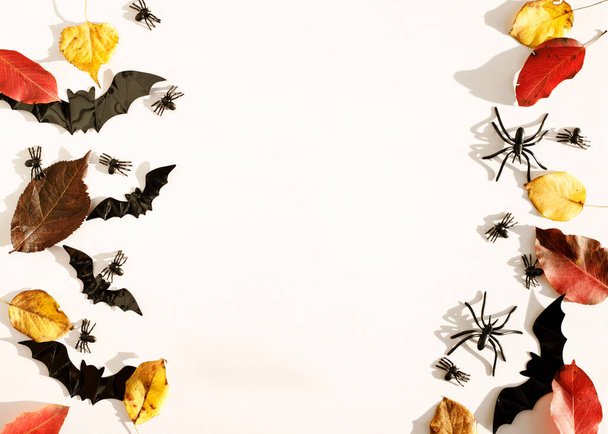 Top view white background with bats, spiders and autumn leaves with copy space for text. Mock up of Halloween holiday concept. - Fotografie, Obrázek