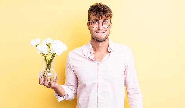 young handsome man looking puzzled and confused. flowers concept - Foto, Imagen