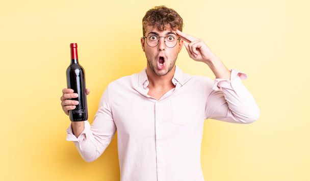 young handsome man looking surprised, realizing a new thought, idea or concept. wine bottle concept - Foto, immagini