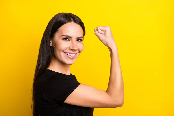 Profile photo of charming satisfied lady arm flexing showing biceps look camera isolated on yellow color background - Fotografie, Obrázek