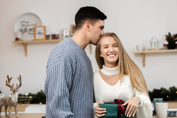 Sweet couple opening Christmas gifts in the living room at home - Foto, Bild