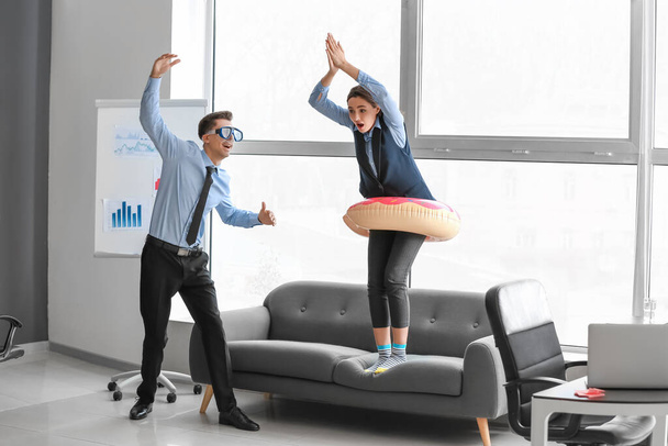 Колеги з надувним кільцем та маскою для снорклінгу розважаються в офісі
 - Фото, зображення
