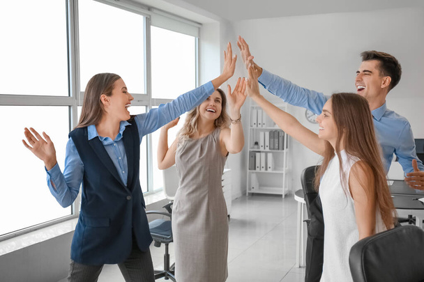 Young colleagues giving high-five to each other in office - Fotó, kép