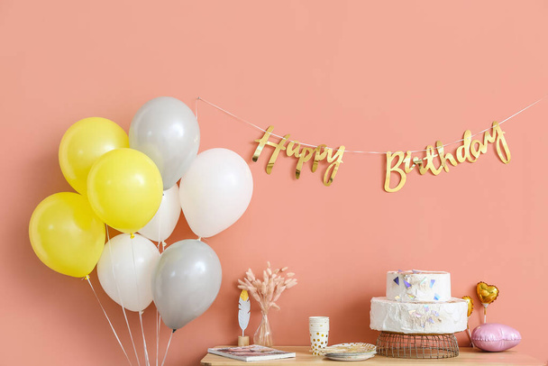 Doğum günü pastası ve renkli duvarın yanında balonlar olan masa. - Fotoğraf, Görsel