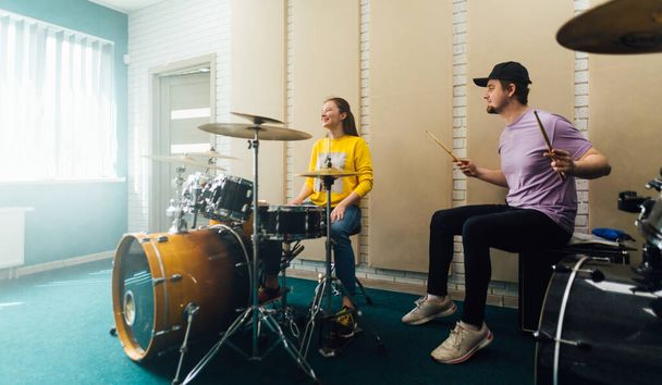 Male teacher showing young woman how to play drums. - Valokuva, kuva