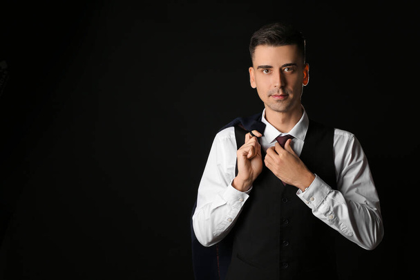 Όμορφος νεαρός άνδρας με κομψό επίσημο κοστούμι σε σκούρο φόντο - Φωτογραφία, εικόνα