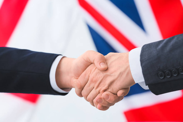 Empresarios apretones de manos contra las banderas de Gran Bretaña e Inglaterra - Foto, Imagen