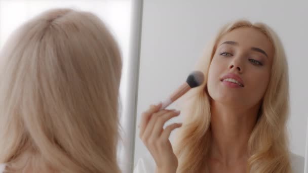 Béküljetek ki. Gyönyörű szőke nő néz tükör és használata kozmetikai kefe - Felvétel, videó