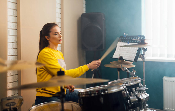 A girl learns how to play the drums from the notes. - Foto, Imagem