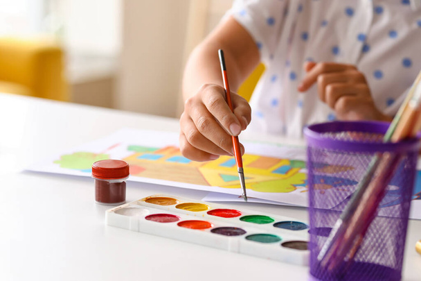 Meisje met penseel en aquarelverf aan tafel, close-up - Foto, afbeelding