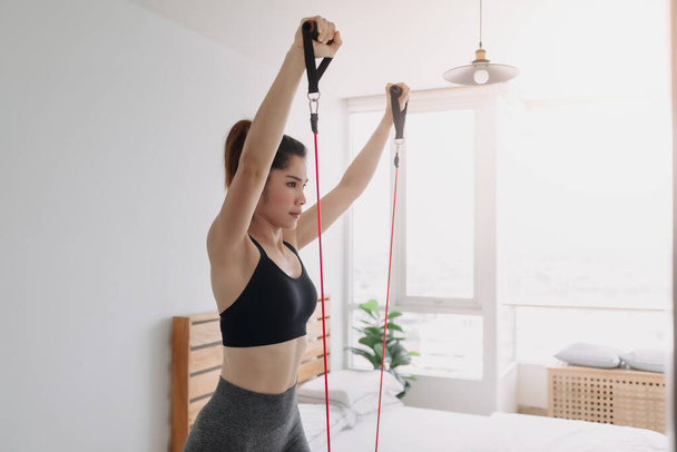 Woman do Resistance Band Upper Chest Press workout in her bedroom. - Foto, Imagen