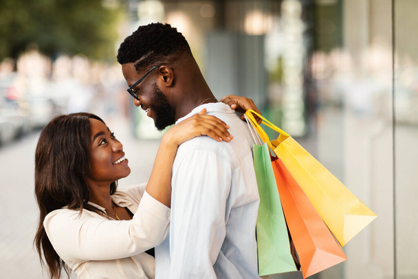 Boldog afro-amerikai pár ölelés és gazdaság bevásárló táskák - Fotó, kép