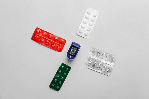 Pulse oximeter with pills on light background - Photo, Image