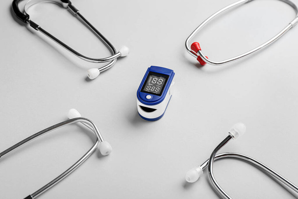 Pulsoximeter und Stethoskope auf hellem Hintergrund - Foto, Bild