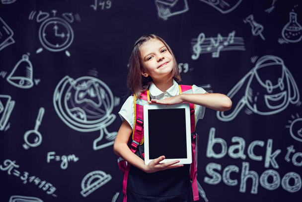 Cute pupil preparing to go to school with backpack showing the tablet. Back to school concept  - Фото, зображення