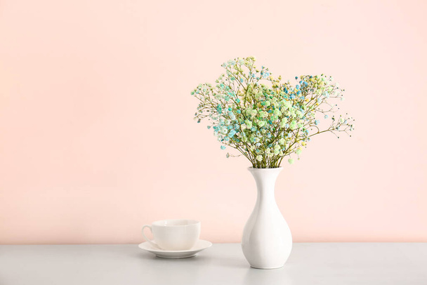 Vase avec de belles fleurs de gypsophila et tasse sur la table - Photo, image