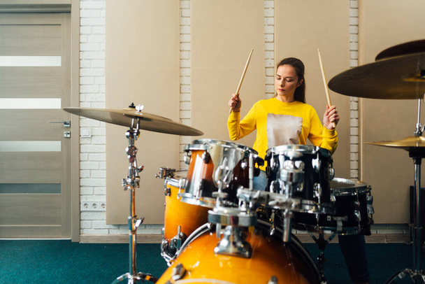 Young woman banging on a drum kit. Playing musical instruments. - Photo, image