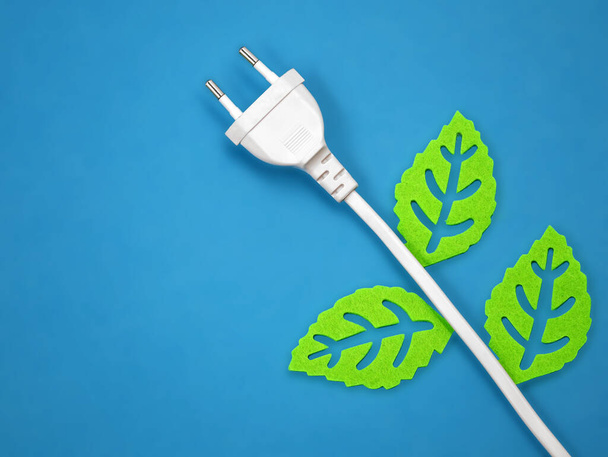 緑の葉が青い背景に隔離された白い電源プラグ緑の生態系エネルギーの概念イメージ - 写真・画像