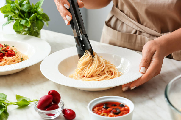 Woman preparing Pasta Puttanesca at kitchen table, closeup - Foto, afbeelding