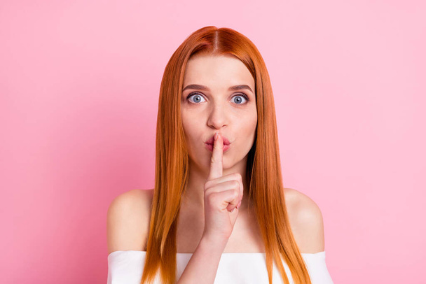 Portrait of attractive amazed mysterious red-haired girl showing shh sign isolated over pink pastel color background - Fotografie, Obrázek