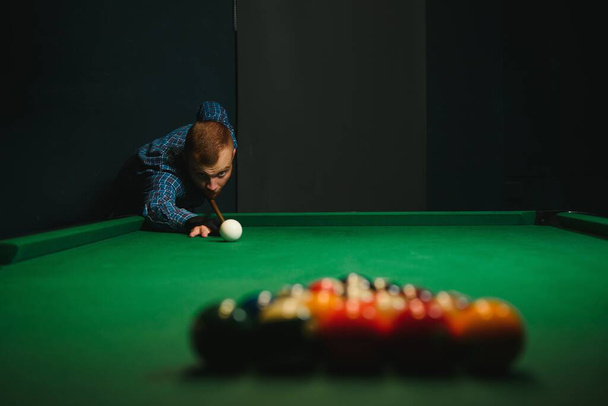 Young handsome man leaning over the table while playing snooker - Фото, изображение