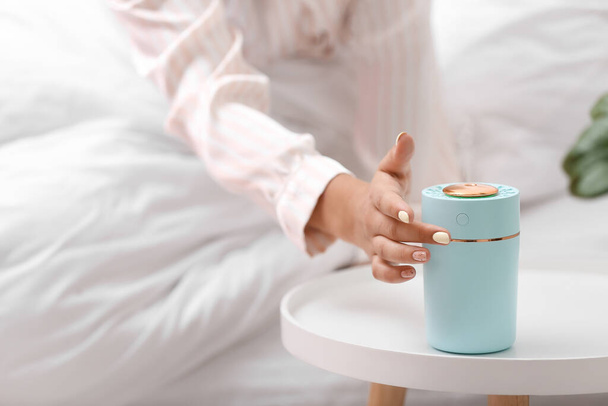 Woman switching on modern air humidifier in bedroom, closeup - Photo, Image