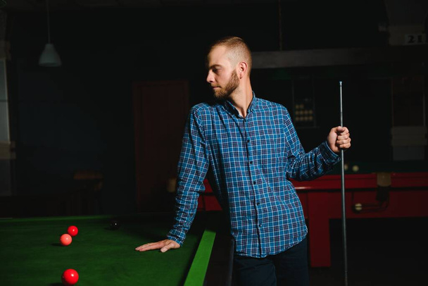 Young handsome man leaning over the table while playing snooker - Photo, Image