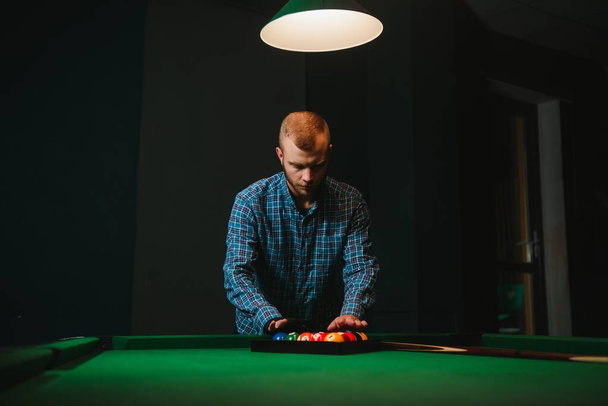 Young handsome man leaning over the table while playing snooker - Foto, afbeelding