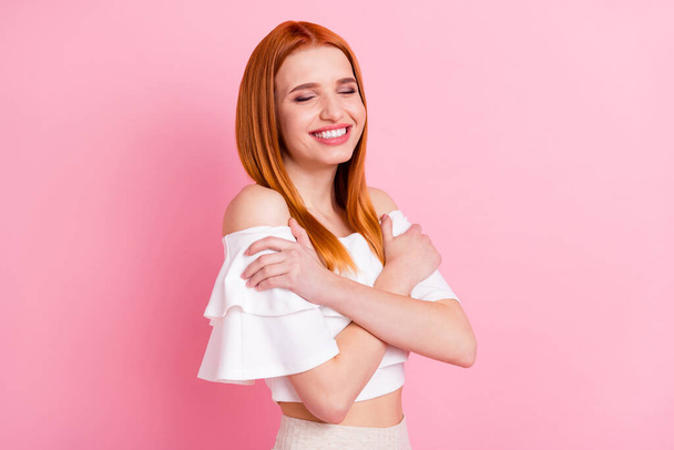 Portrait of attractive dreamy cheerful red-haired girl hugging herself harmony idyllic isolated over pink pastel color background - Fotó, kép