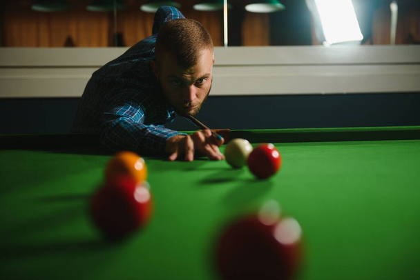 Young handsome man leaning over the table while playing snooker - Foto, Bild