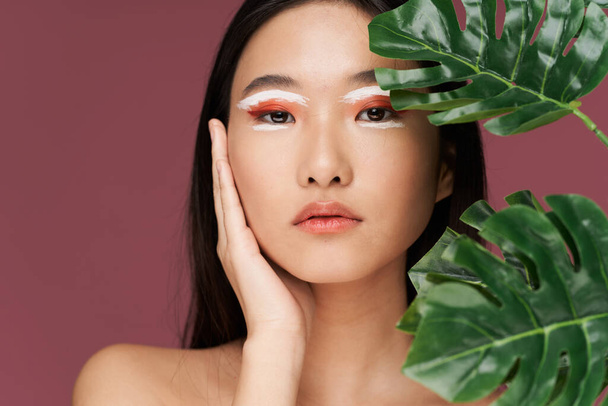 Mulher asiática maquiagem brilhante folhas verdes ombros nus pele clara - Foto, Imagem