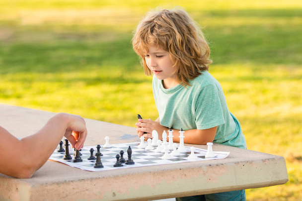 syn dziecko gra w szachy na stole w parku odkryty z ojcem, dzieciństwo - Zdjęcie, obraz