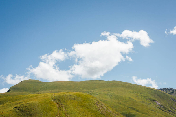 schilderachtig uitzicht op grazige heuvel tegen een blauwe lucht - Foto, afbeelding